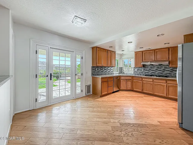 a kitchen with granite countertop wooden cabinets a sink a stove a dining table and chairs with wooden floor