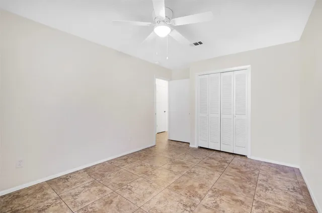 an empty room with a ceiling fan and carpet