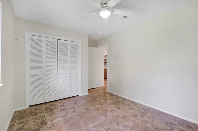 an empty room with a fan & a window