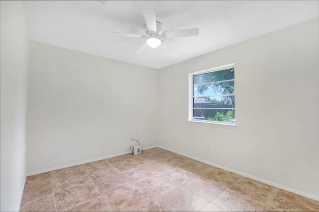 an empty room with a ceiling fan and window