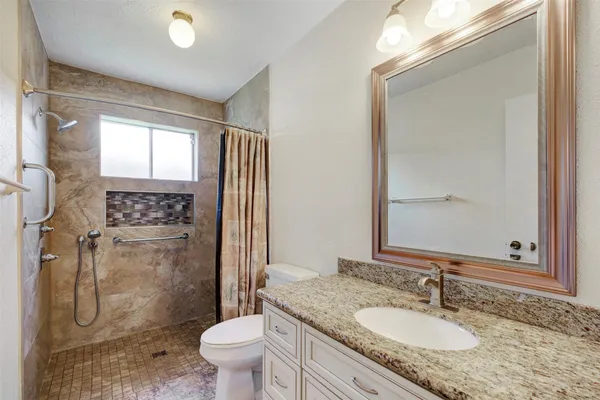 a bathroom with a granite countertop sink toilet and shower