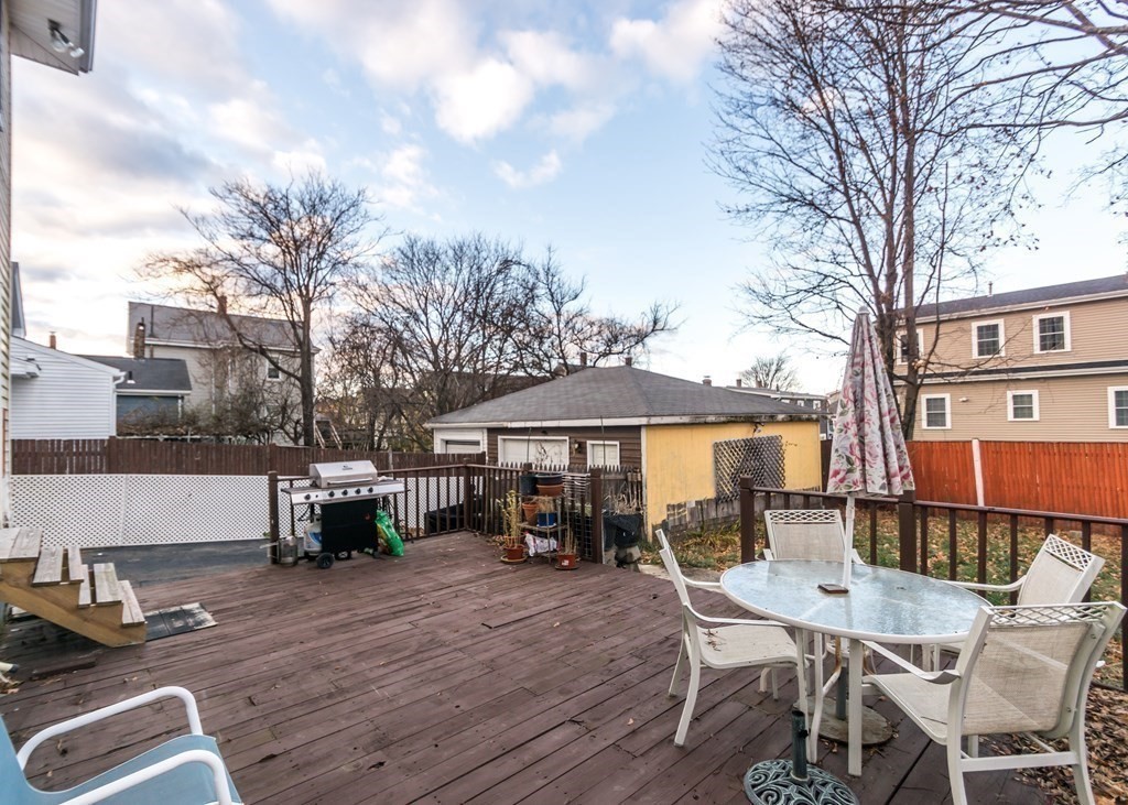 28 Bolton Street Waltham, MA 02453 - Photo 20 of 22 a view of a patio with table and chairs with wooden floor and fence
