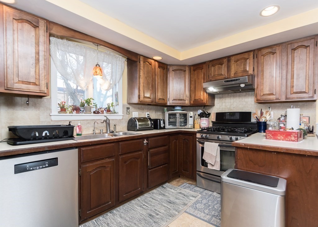 28 Bolton Street Waltham, MA 02453 - Photo 5 of 22 a kitchen with stainless steel appliances granite countertop a stove sink microwave and cabinets