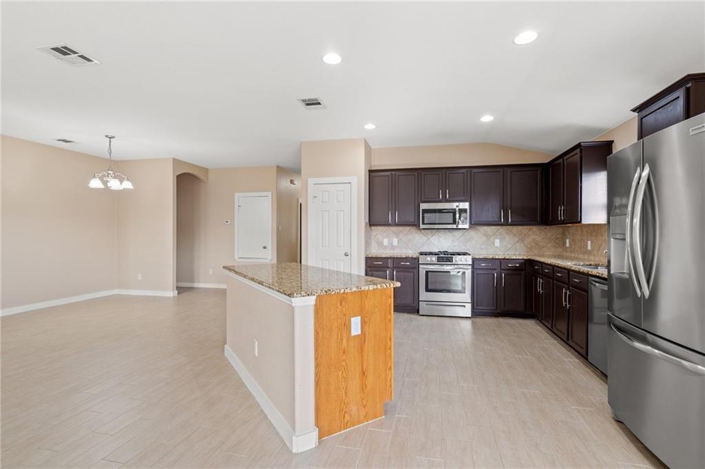 20224 Merlin Falcon Trail Pflugerville, TX 78660 - Photo 20 of 40 A well-appointed kitchen features dark wood cabinetry, granite countertops, and modern stainless steel appliances.