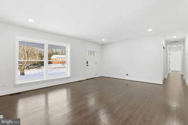 an empty room with wooden floor and window