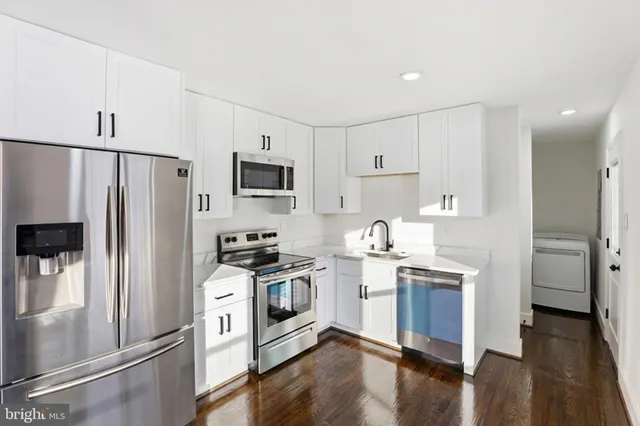 a kitchen with cabinets stainless steel appliances and wooden floor