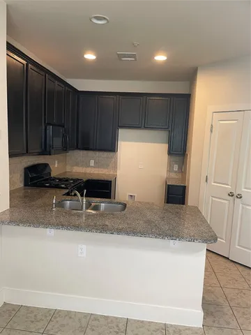 a view of kitchen island a sink wooden floor and entryway