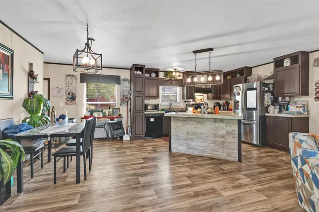 a kitchen with stainless steel appliances kitchen island granite countertop a table chairs and a refrigerator