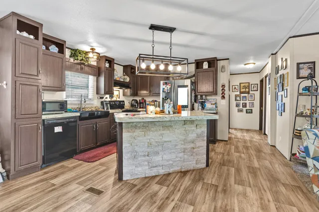 a kitchen with stainless steel appliances granite countertop a refrigerator a oven a stove and a wooden floors