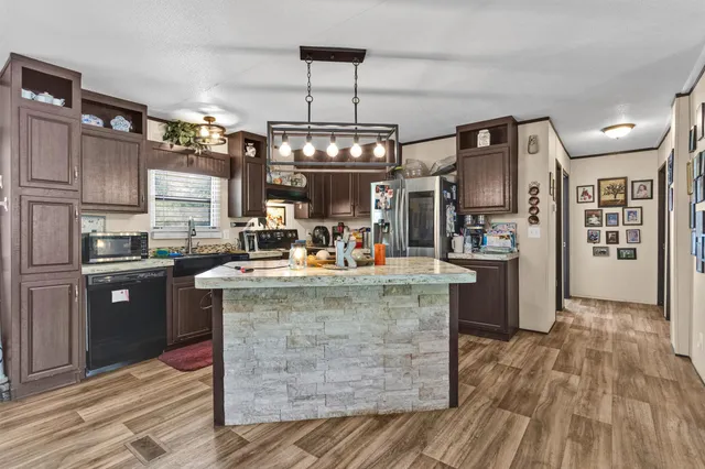 a kitchen with kitchen island a counter top space a sink stainless steel appliances and cabinets