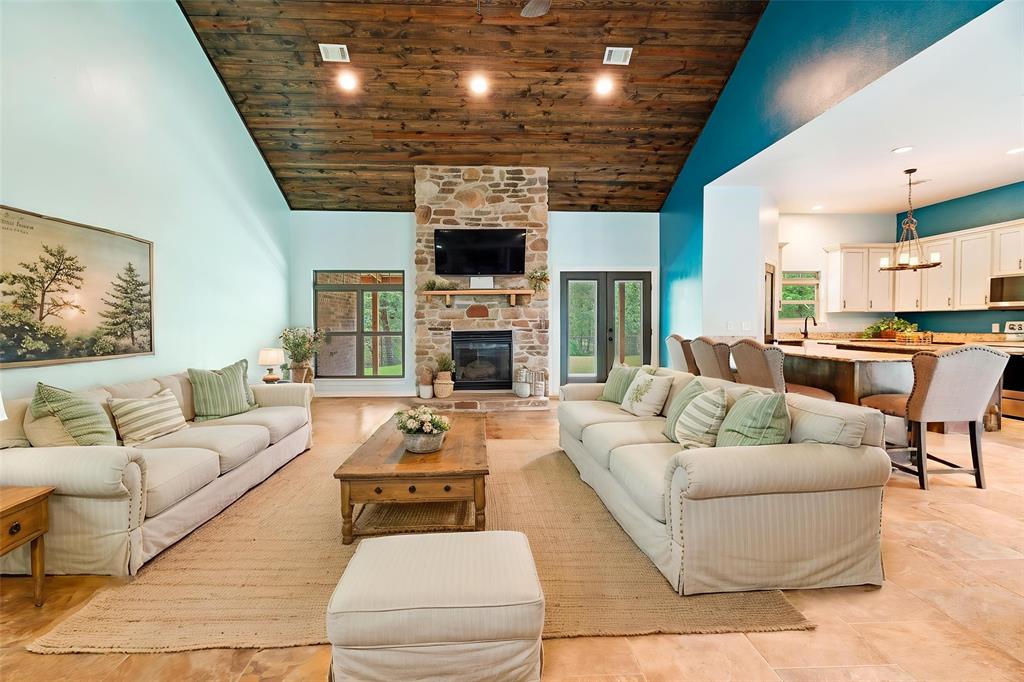 821 County Road Paris, TX 75462 - Photo 5 of 40 Spacious living area featuring a vaulted wood-finish ceiling, stone fireplace with hearth, and tiled flooring