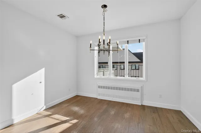 a view of a room with wooden floor chandelier and windows