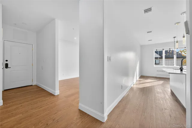 a view of a hallway with wooden floor and a kitchen