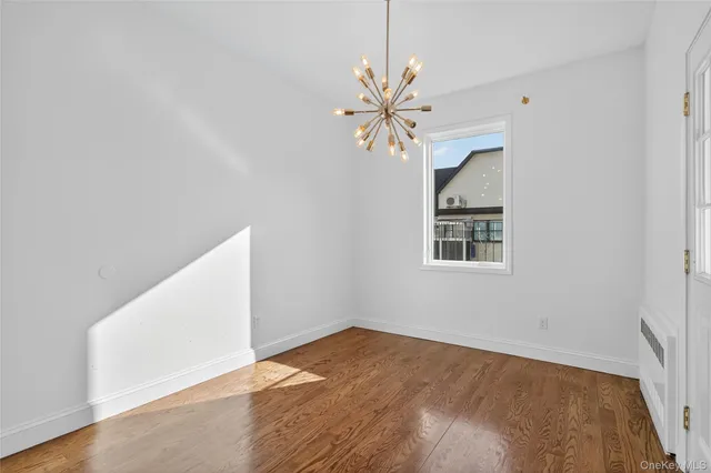 an empty room with wooden floor chandelier fan and windows