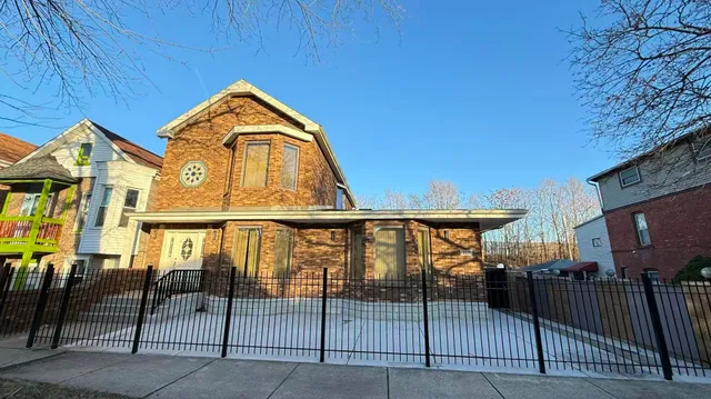 a view of a brick house with iron fence