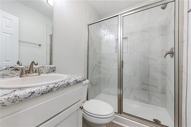 a bathroom with a granite countertop sink toilet and shower