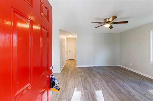 a view of empty room with a fan and wooden floor