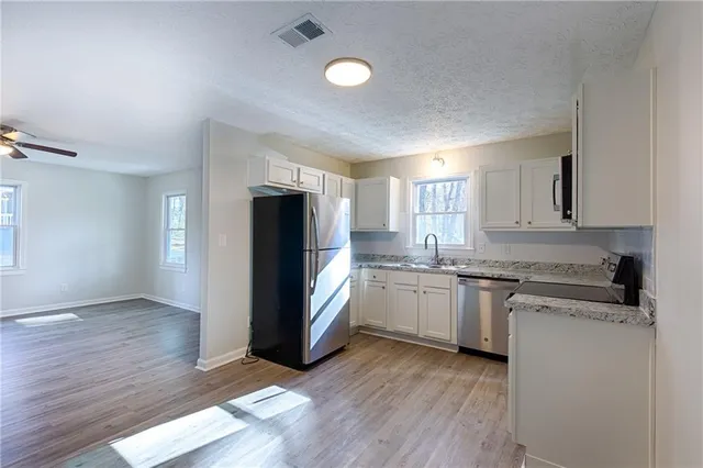 a kitchen with granite countertop stainless steel appliances refrigerator sink and cabinets