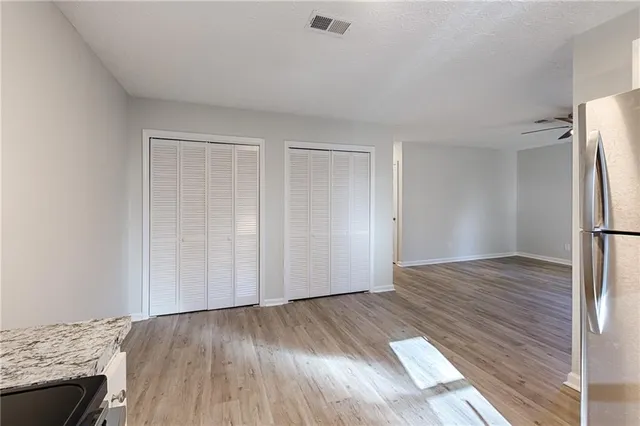 a view of empty room with wooden floor and fan
