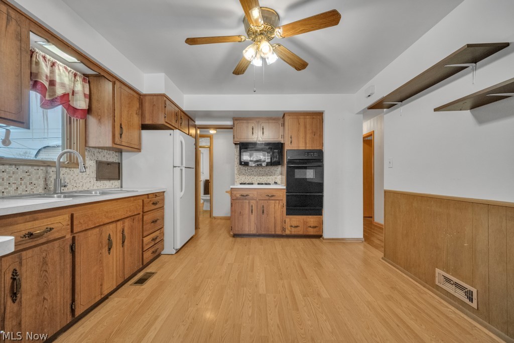 6846 Revere Road Cleveland, OH 44130 - Photo 12 of 30 Kitchen with a ceiling fan, black appliances, light countertops, wood finish cabinets, and decorative backsplash