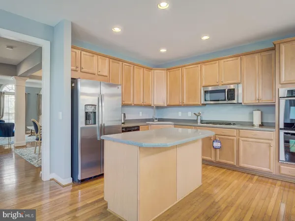 a living room with couches and a flat screen tv with kitchen view