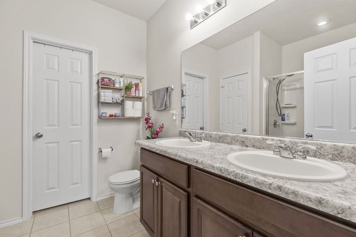 209 Ibis Falls Loop Jarrell, TX 76537 - Photo 21 of 40 a bathroom with a granite countertop sink a toilet and a mirror