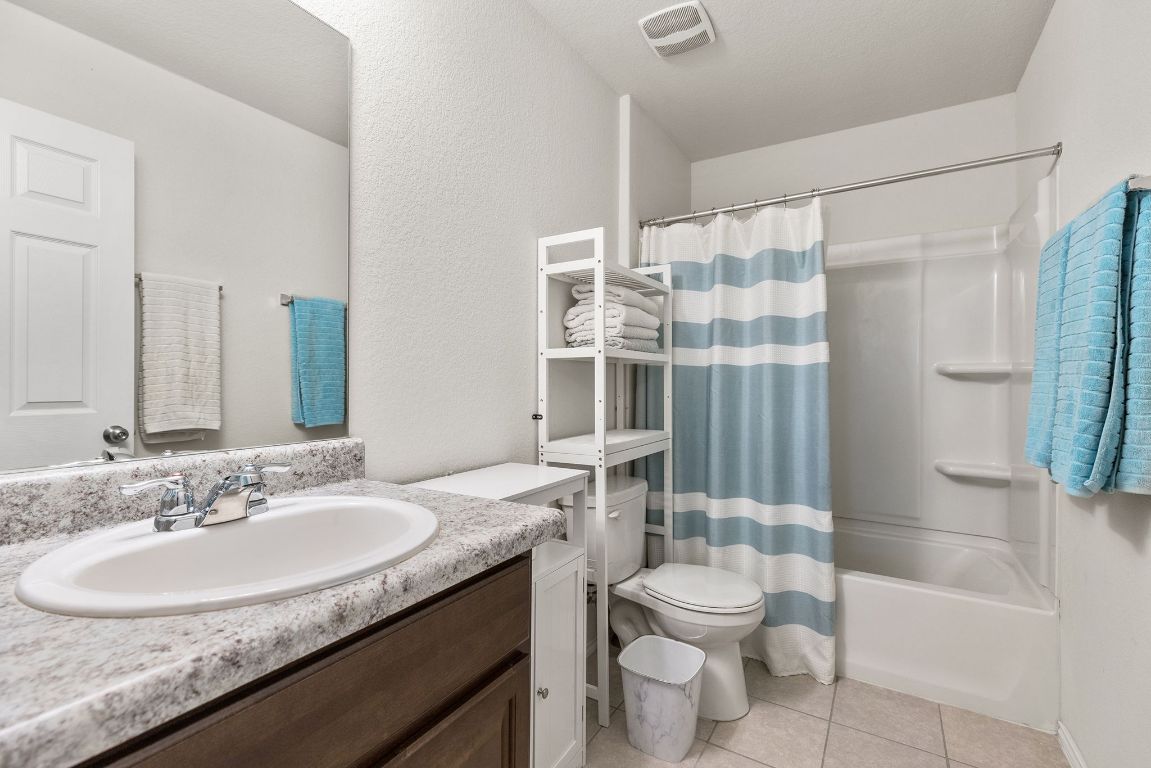 209 Ibis Falls Loop Jarrell, TX 76537 - Photo 28 of 40 a bathroom with a granite countertop sink toilet a mirror a vanity and shower