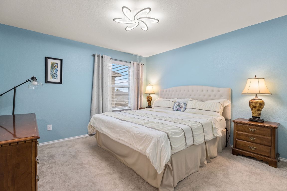 209 Ibis Falls Loop Jarrell, TX 76537 - Photo 29 of 40 a bedroom with a bed and a chandelier