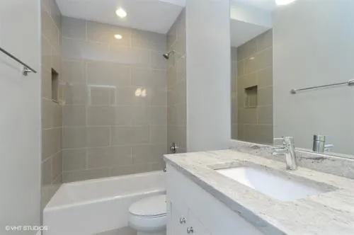 a bathroom with a granite countertop sink a toilet and bathtub