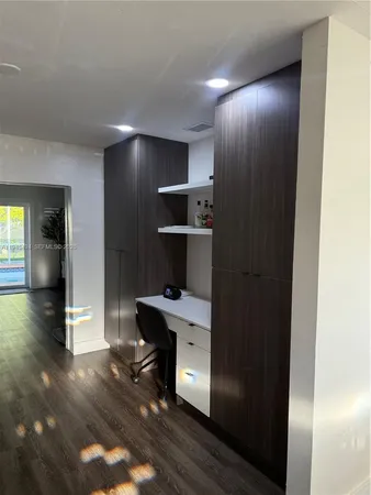 a view of a hallway to room with wooden floor