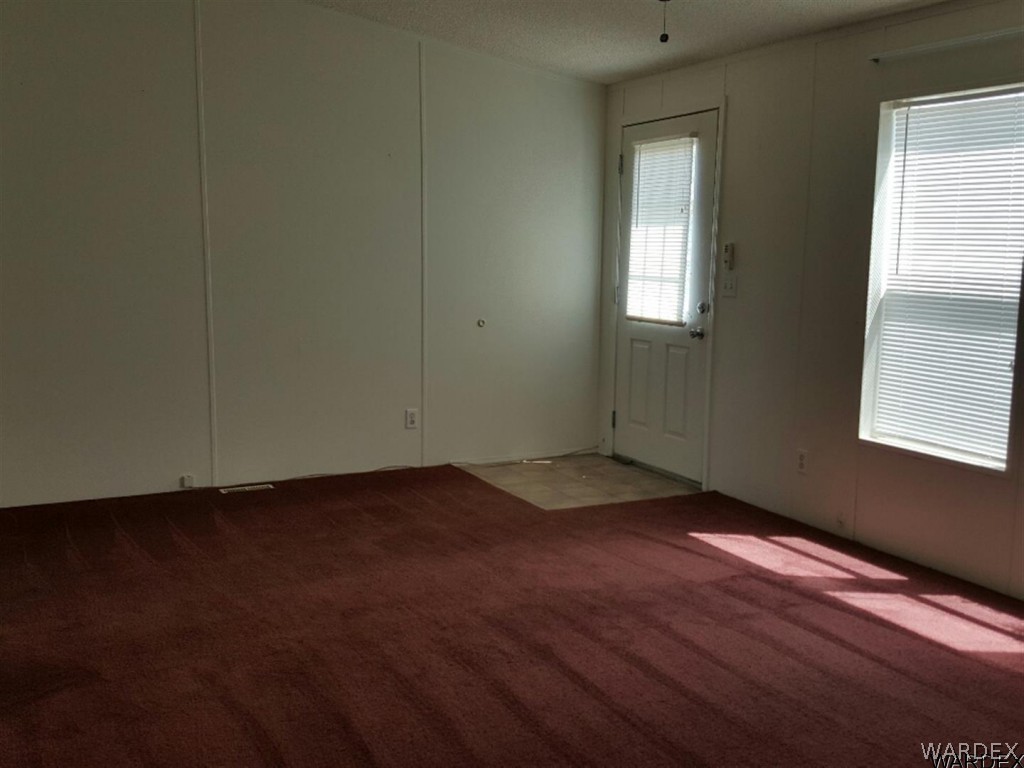1097 South Concho Road Golden Valley, AZ 86413 - Photo 9 of 20 an empty room with wooden floor and windows
