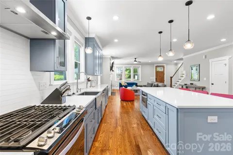 a large kitchen with kitchen island a stove a sink a counter top space and living room view