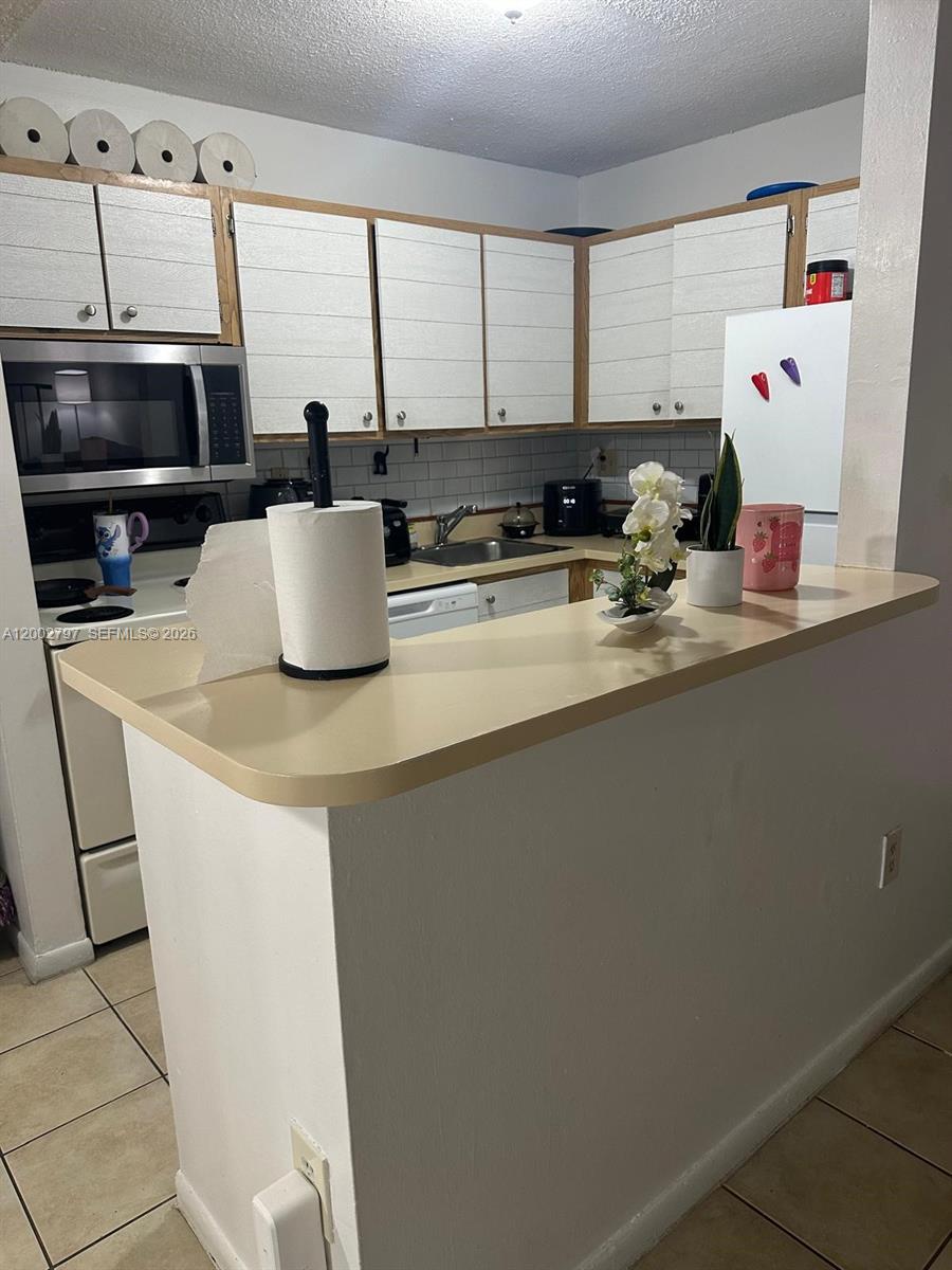 7220 Northwest 179th Street, Unit 111 Hialeah, FL 33015 - Photo 8 of 12 a kitchen with a sink a stove and cabinets