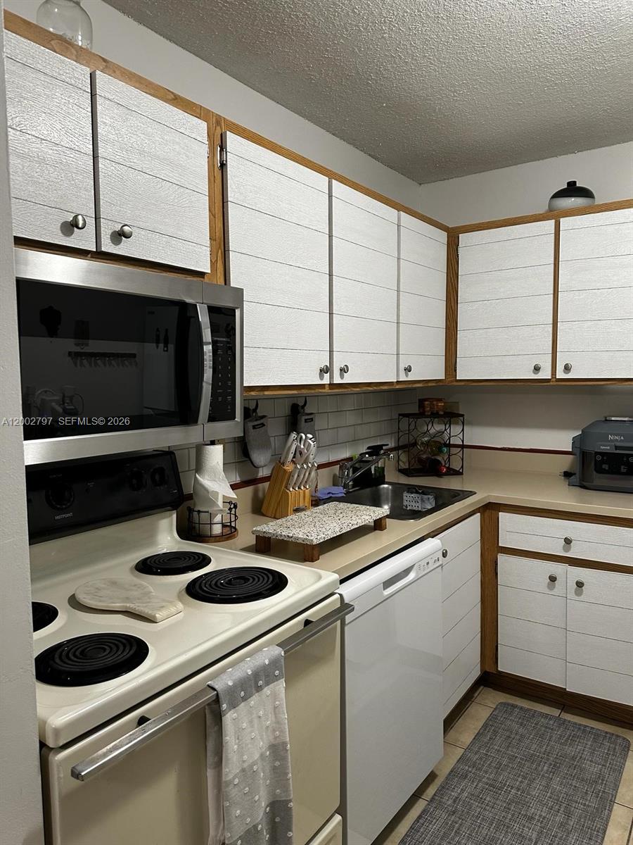 7220 Northwest 179th Street, Unit 111 Hialeah, FL 33015 - Photo 9 of 12 a kitchen with stainless steel appliances granite countertop a sink a stove and a microwave