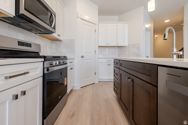 4748 Heartwood Road, Unit 434 Mapleton, UT 84664 - Photo 7 of 18 Kitchen with stainless steel appliances, two tone cabinetry, light wood-type flooring, decorative backsplash, and recessed lighting