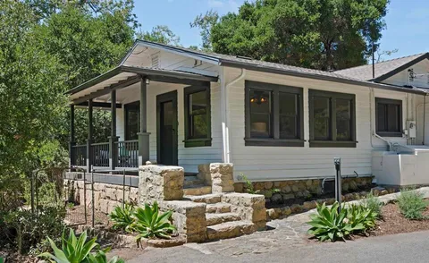 a front view of a house with large windows and potted plants