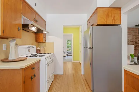 a kitchen with stainless steel appliances granite countertop a refrigerator a stove and a wooden floor