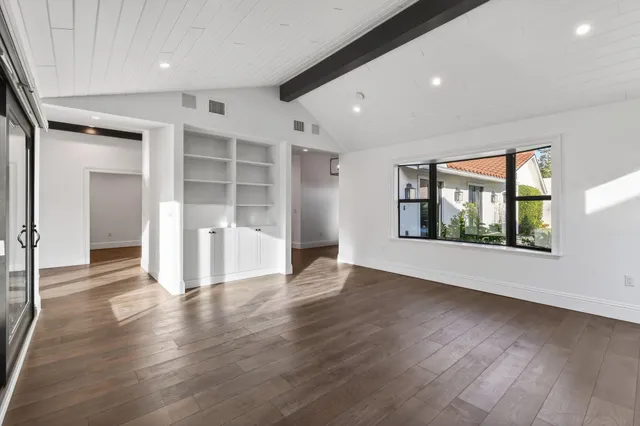 a view of an empty room with a window and wooden floor