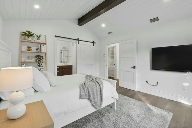 a spacious bedroom with a bed and a flat screen tv