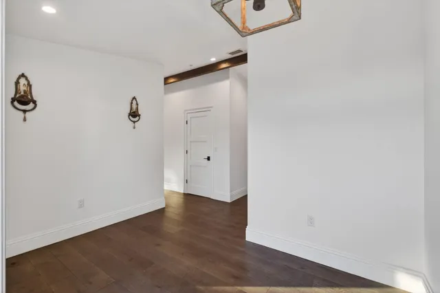 an empty room with a wooden floor and mirror