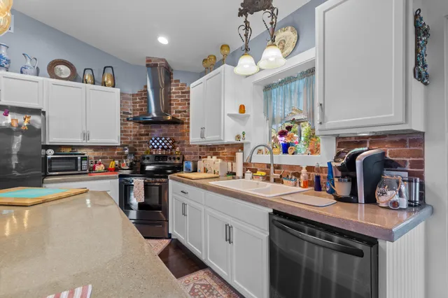 a kitchen with stainless steel appliances kitchen island granite countertop a table chairs in it and a sink