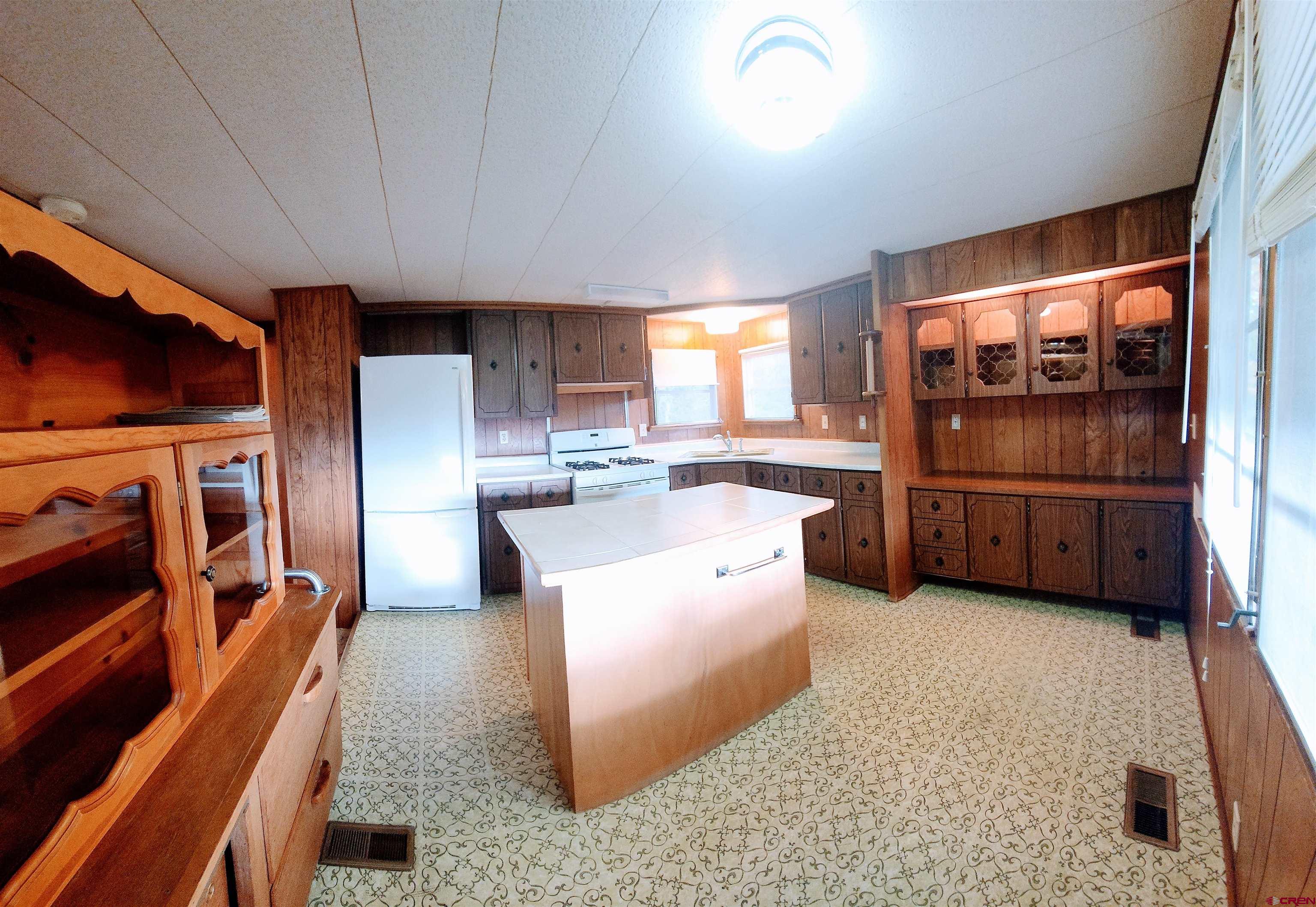 24593 Timothy Road Cedaredge, CO 81413 - Photo 18 of 33 a kitchen with stainless steel appliances granite countertop a refrigerator a stove and a sink with wooden floor
