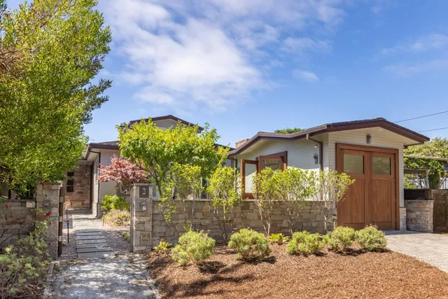 a front view of a house with a yard and a lot of flower plant