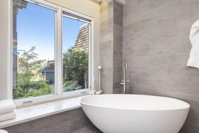a white bath tub sitting in a bathroom next to a window