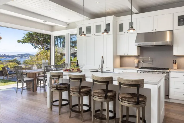 a kitchen with stainless steel appliances granite countertop a table chairs stove and wooden floor