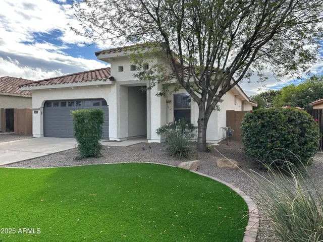 a view of a yard in front of a house with a large tree