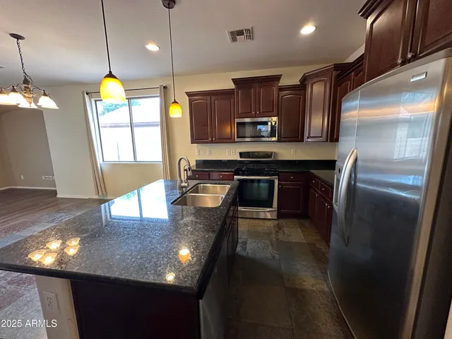 a large kitchen with granite countertop a stove top oven a sink dishwasher a dining table and chairs with wooden floor