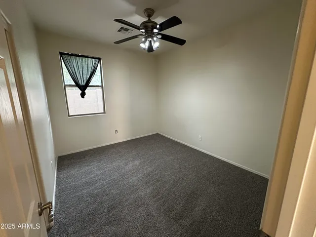 a view of an empty room and chandelier fan and fire place