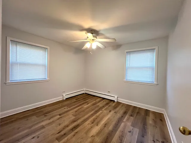 a view of a room with wooden floor and a chandelier fan