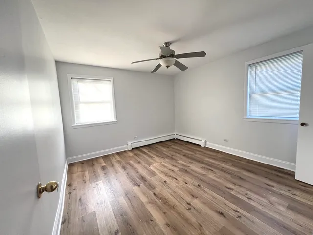 a view of empty room with wooden floor and fan
